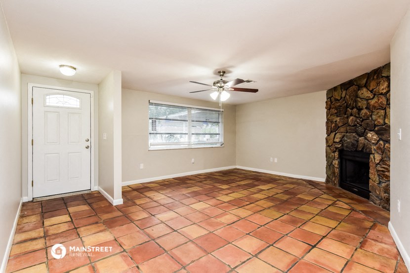 an empty living room with a fireplace and a ceiling fan