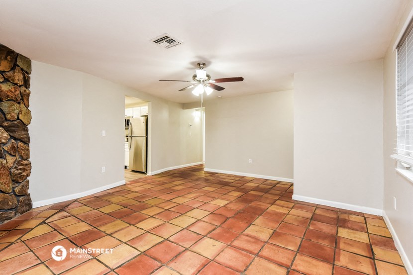 an empty living room with a ceiling fan and tile flooring