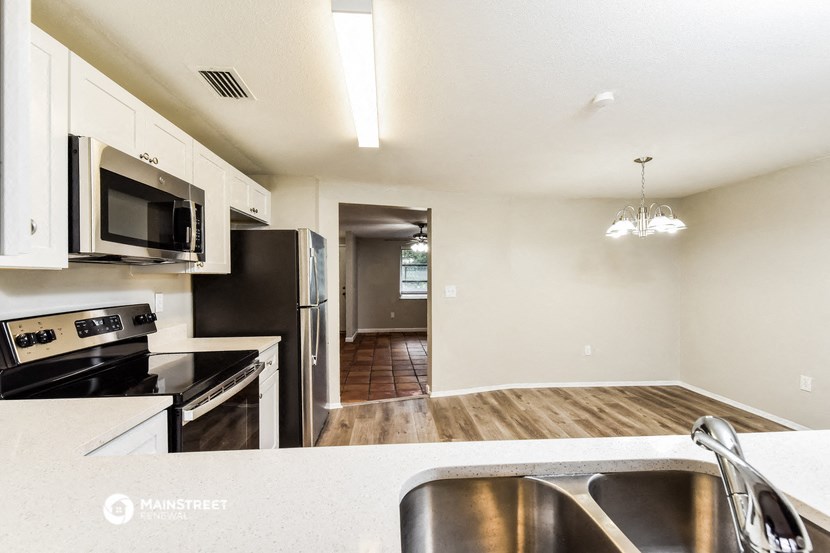 an empty kitchen with stainless steel appliances and white cabinets