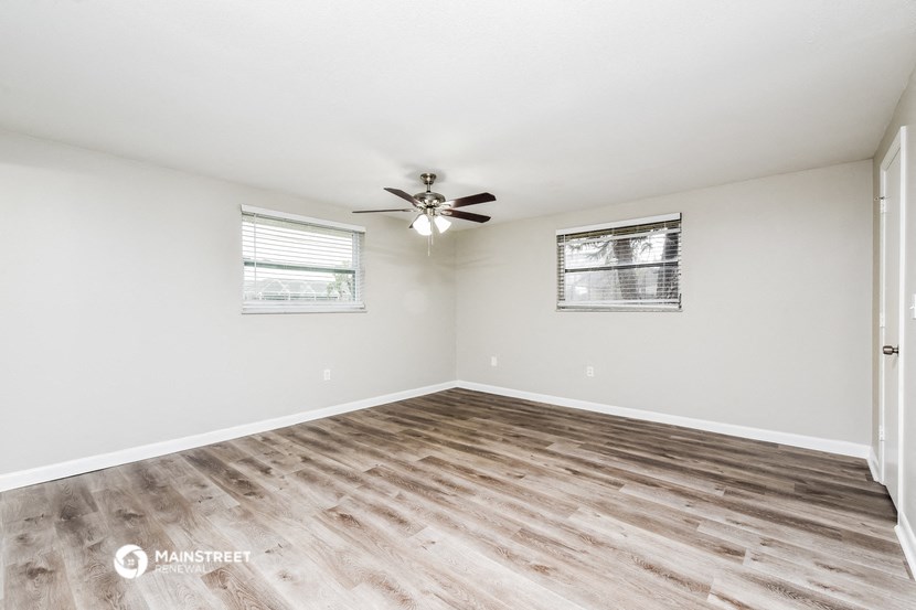 the spacious living room with hardwood floors and a ceiling fan