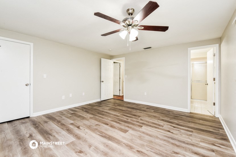 an empty living room with wood floors and a ceiling fan