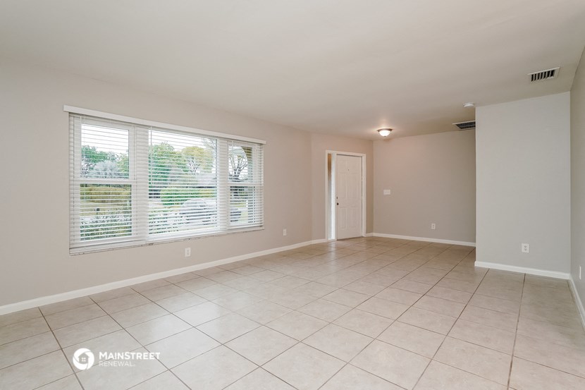 the spacious living room with large windows and tiled flooring