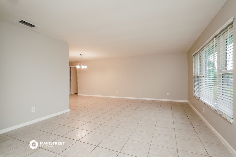 a spacious living room with tiled flooring and a large window