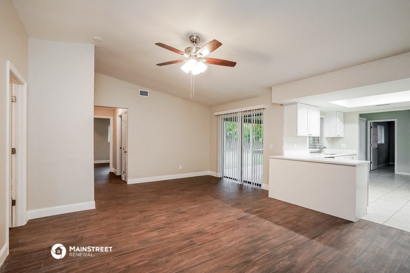 an empty living room and kitchen with a ceiling fan