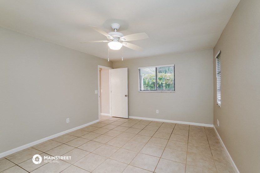 the spacious living room with ceiling fan and tile flooring