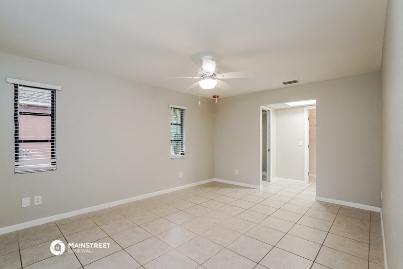 a spacious living room with tile flooring and a ceiling fan