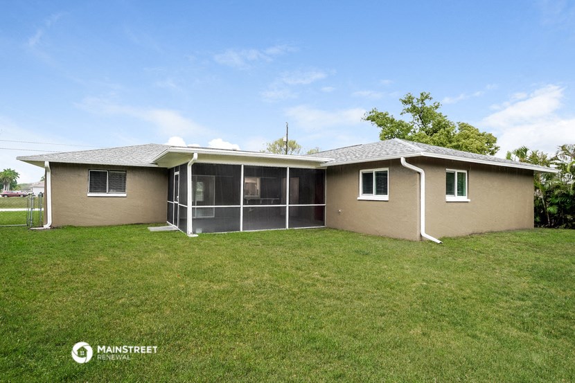a small tan house with a lawn and a screened in porch