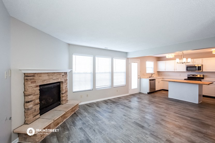 a living room with a fireplace and a kitchen