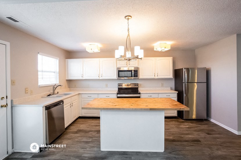 a kitchen with white cabinets and stainless steel appliances and a wooden counter top
