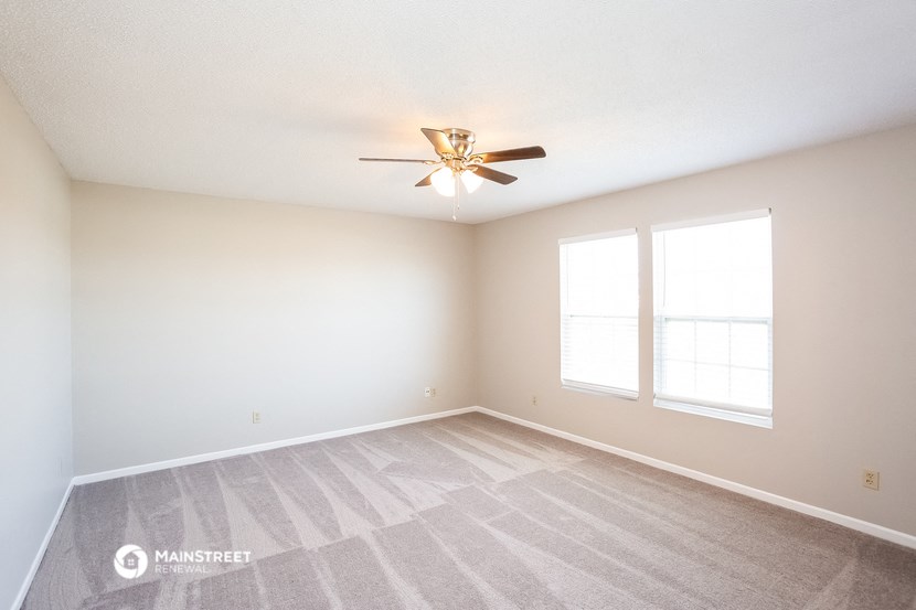 the spacious living room with carpet and ceiling fan