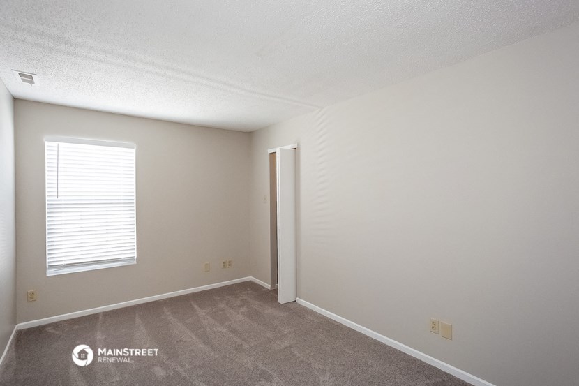 a bedroom with a door to a closet and a window