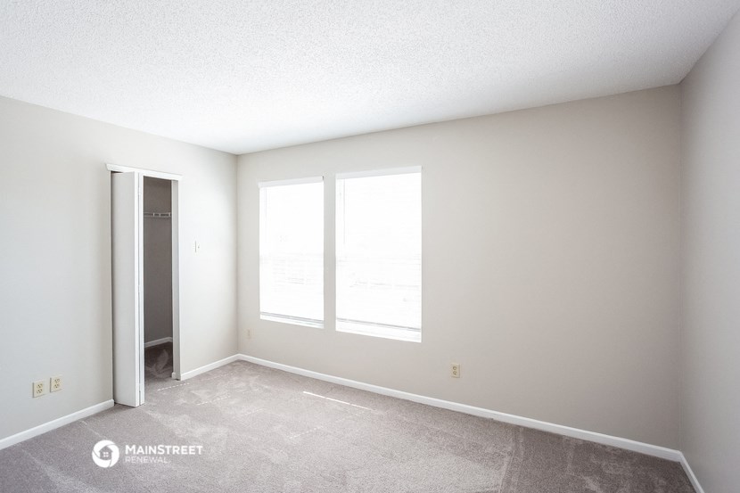 the spacious living room with large windows and concrete flooring
