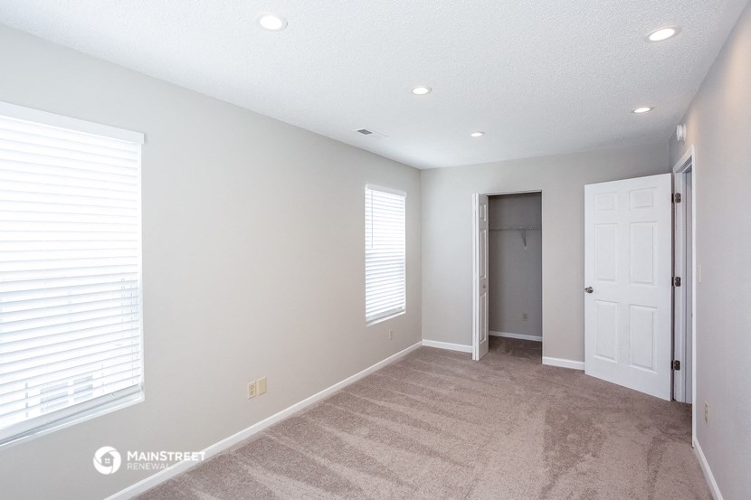 a living room with a carpeted floor and a door to a closet