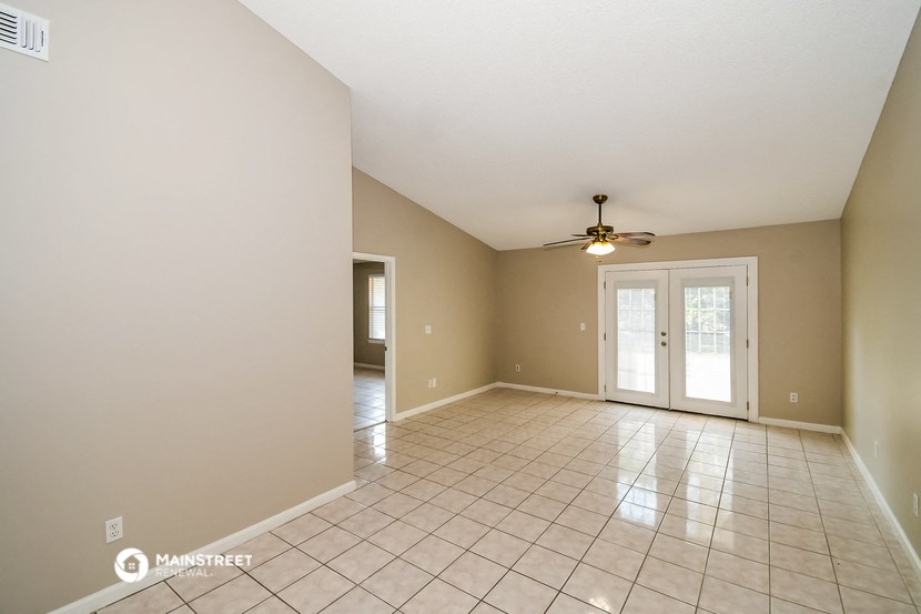 an empty living room with tile flooring and a ceiling fan