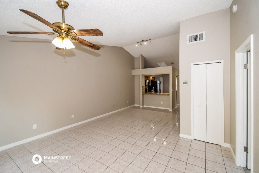 an empty living room with a ceiling fan and a tiled floor
