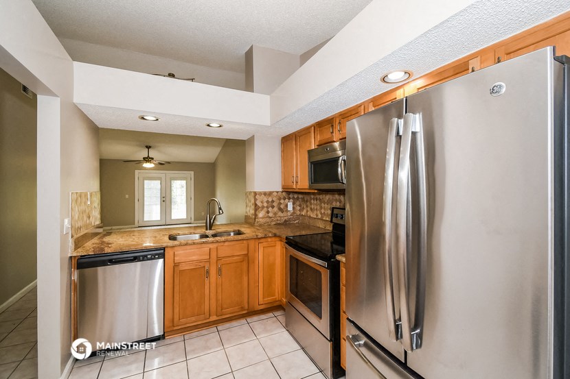the kitchen is equipped with stainless steel appliances and wood cabinets
