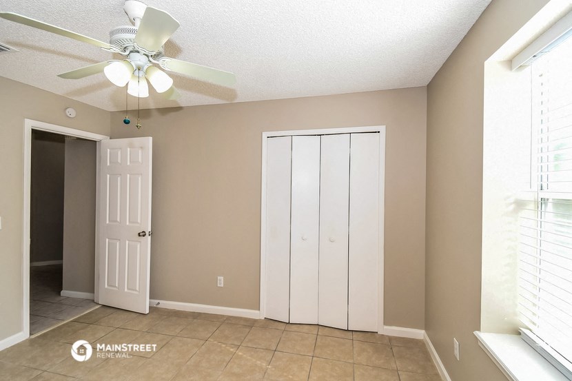 a living room with a ceiling fan and a closet