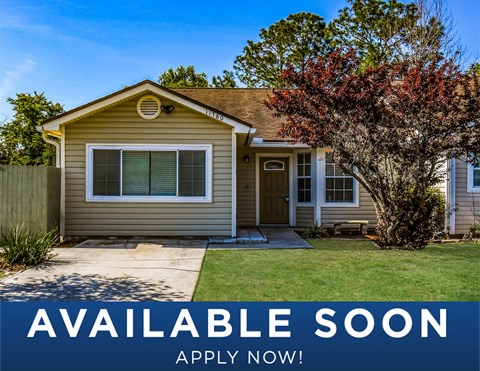 a tan house with a yard and a tree
