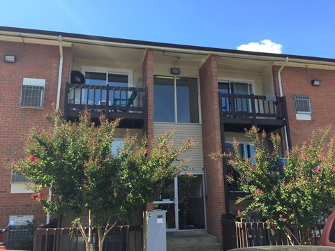 the front of a brick house with two balconies and trees