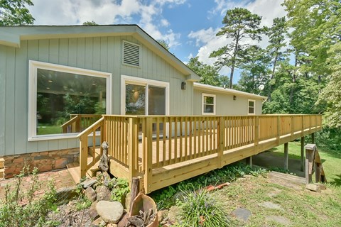 the front of a green house with a wooden deck