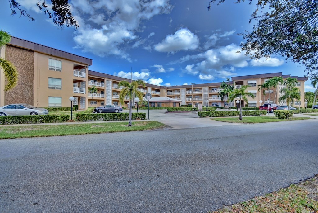 an empty street in front of an apartment building with palm trees