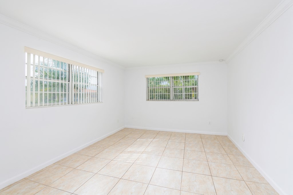 an empty room with white walls and tiled floors and two windows