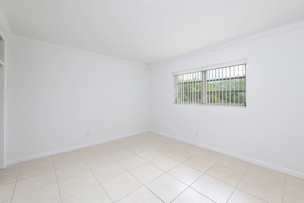 an empty living room with a window and a tiled floor