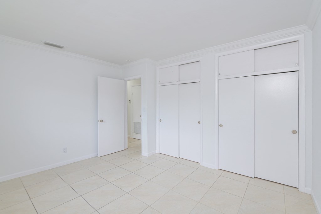 an empty room with white cabinets and a tiled floor