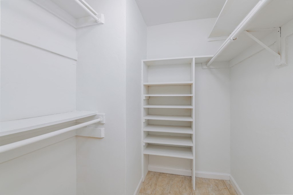 a walk in closet with empty shelves and a white wall