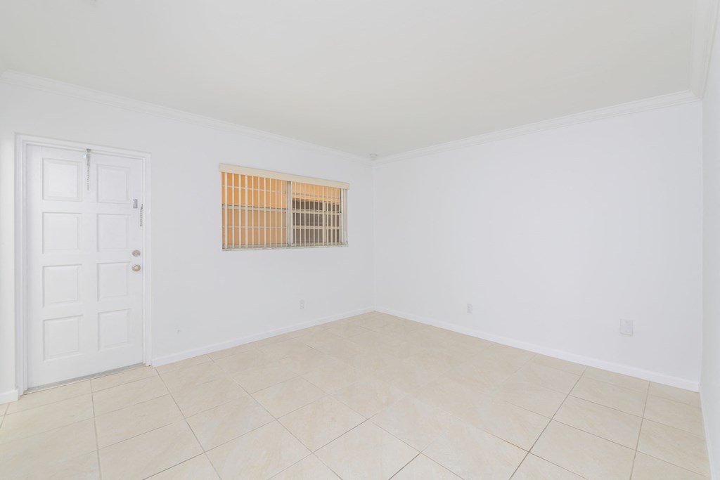 an empty living room with white walls and tile floor and a white door