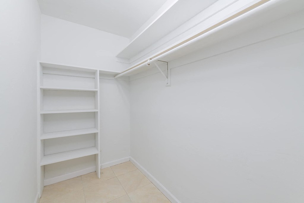 a room with white walls and a closet with shelves