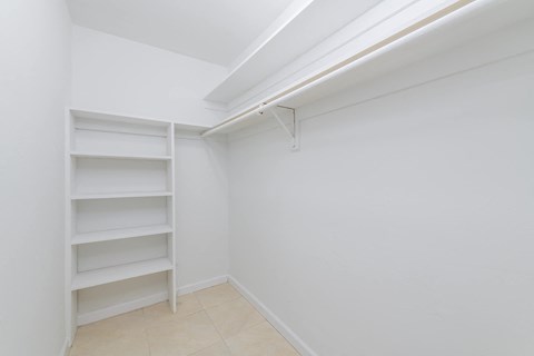 a room with white walls and a closet with shelves