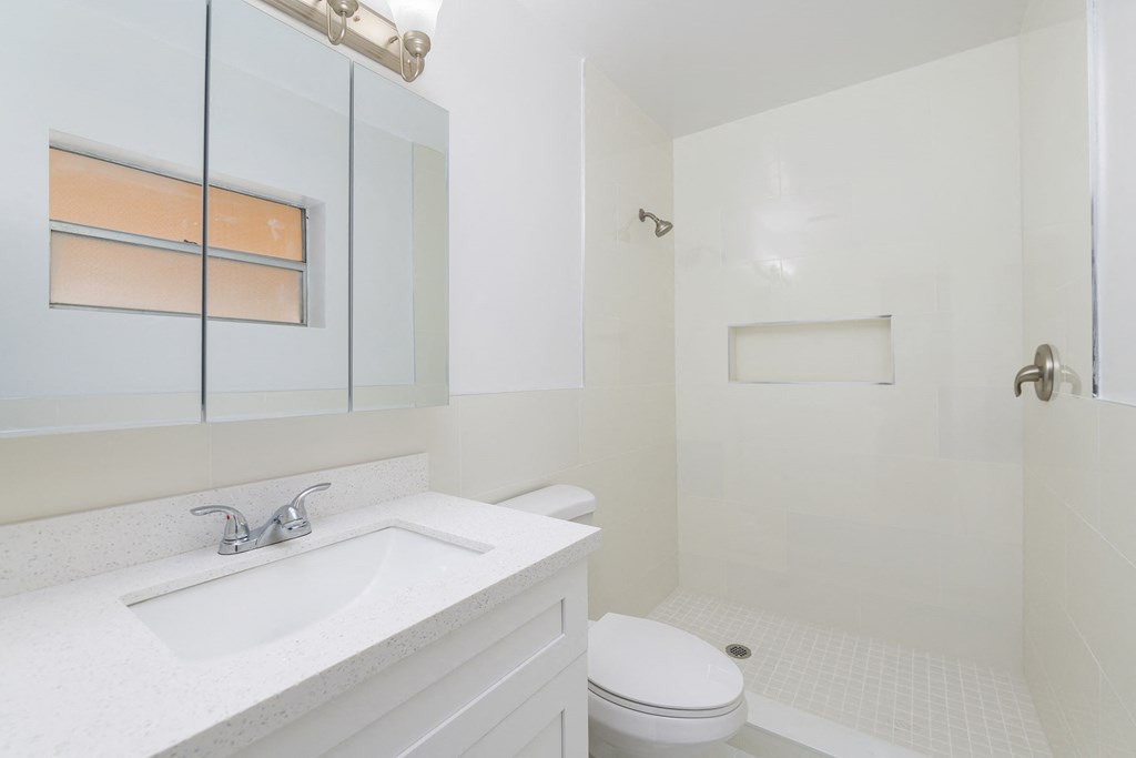 a white bathroom with a sink toilet and shower