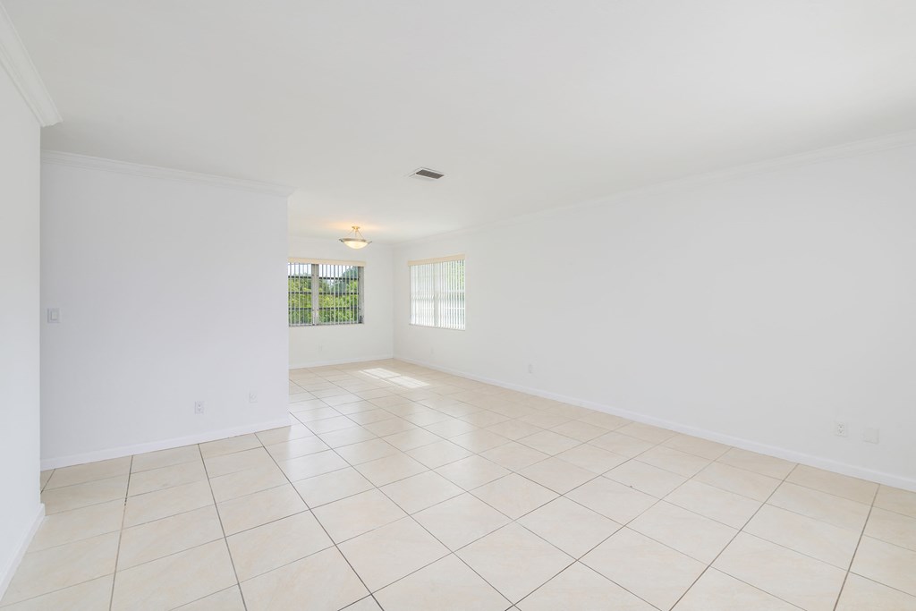 the living room and dining room of a house with white walls and tiled floors