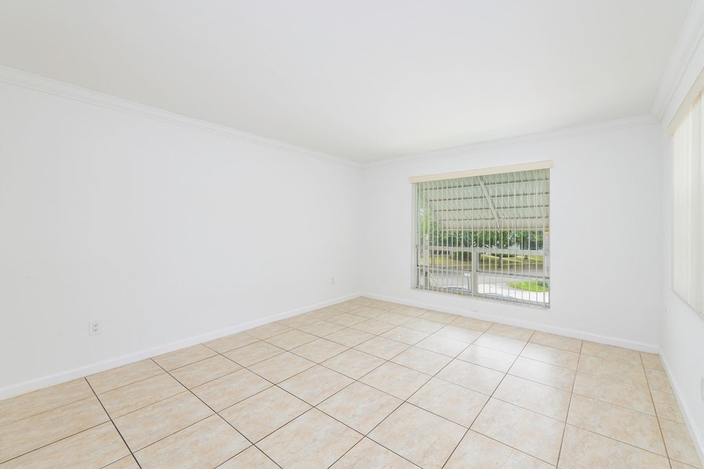 an empty living room with a window and a tiled floor