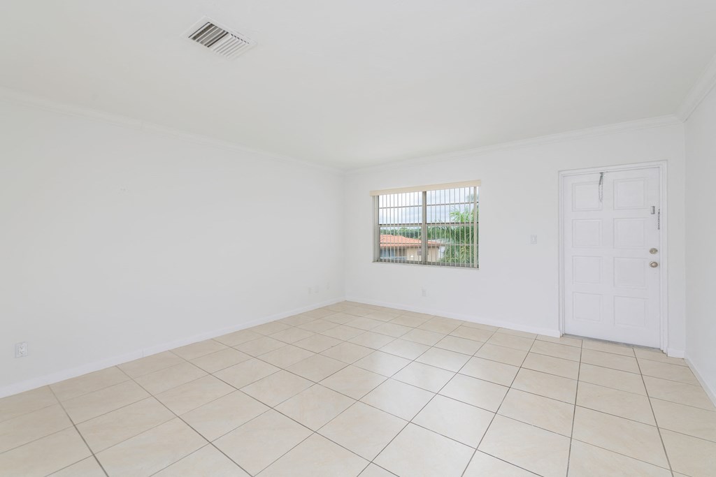 the living room of an empty house with a window and tiled floor