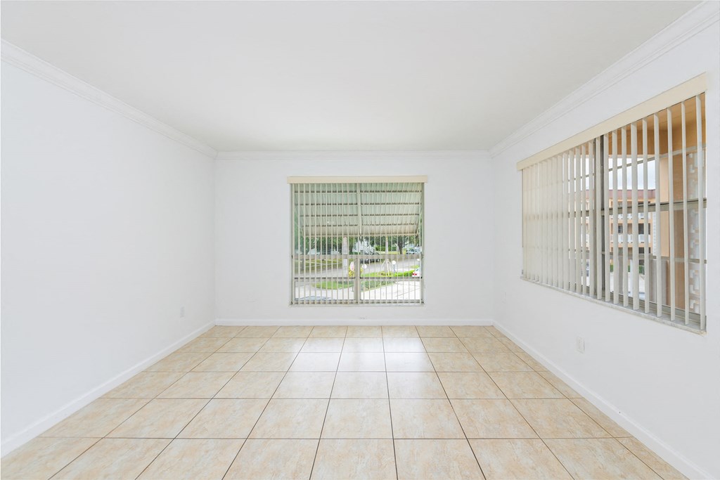 an empty living room with a window and a tiled floor