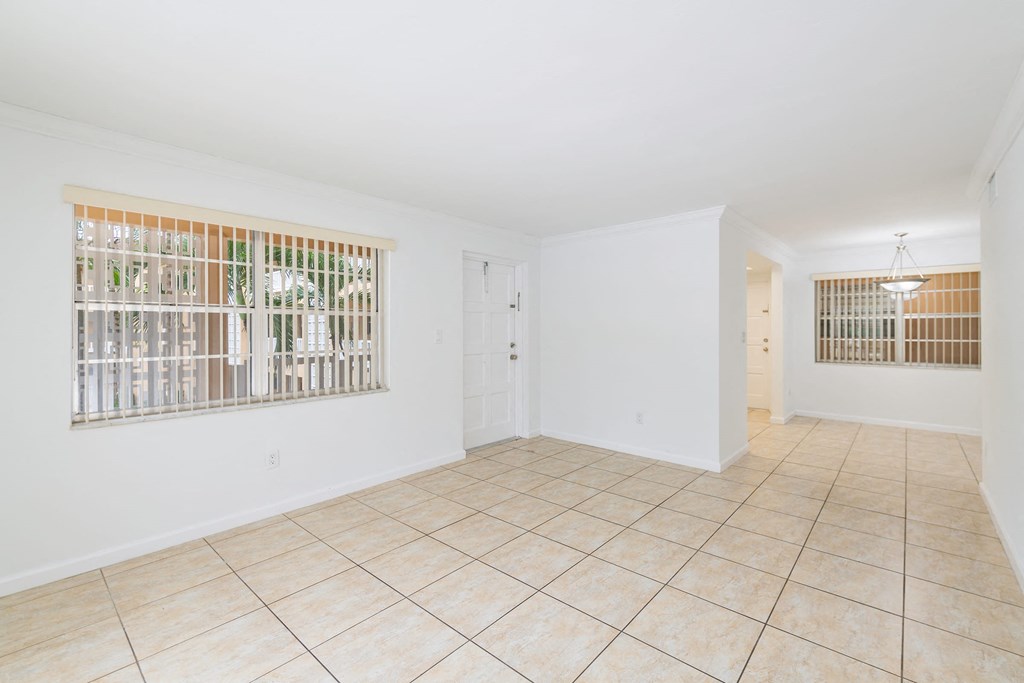 the living room and dining room of an empty house with a large window and tile