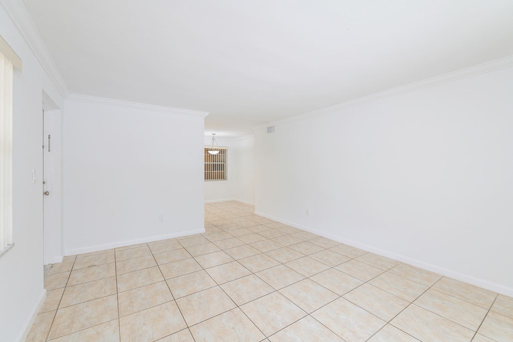 an empty living room with white walls and a tiled floor