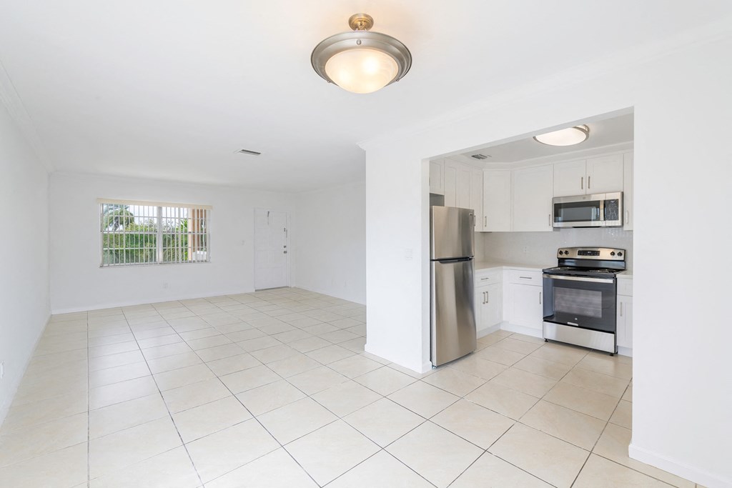 a white kitchen with a stainless steel refrigerator and stove