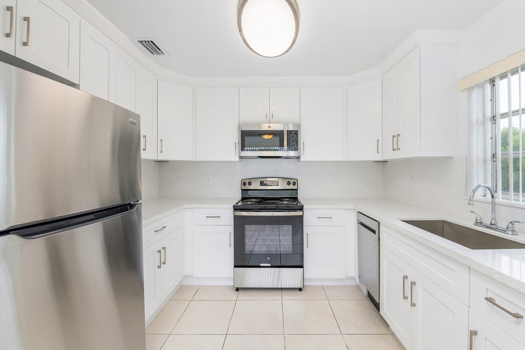 a white kitchen with stainless steel appliances and white cabinets