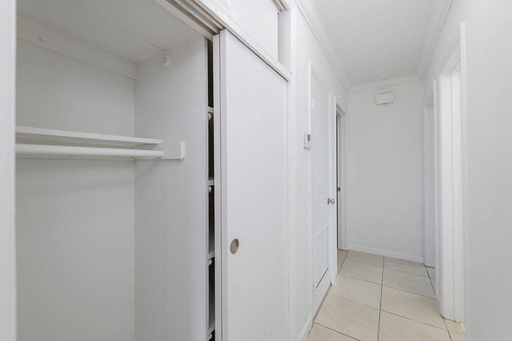 a hallway with white walls and white doors and a tiled floor