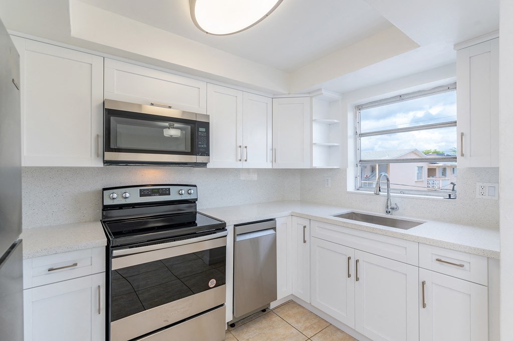 a kitchen with white cabinets and stainless steel appliances and a window