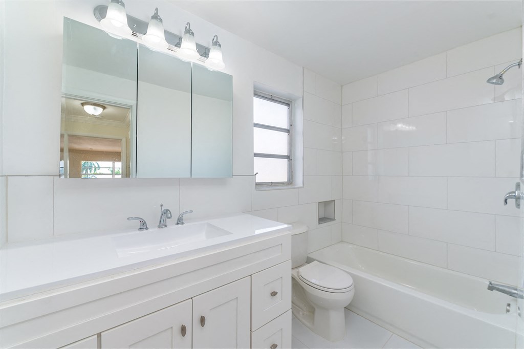 a white bathroom with a tub and a sink and a toilet