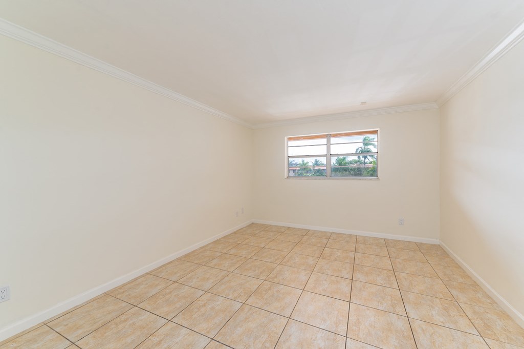 an empty living room with tiled flooring and a window