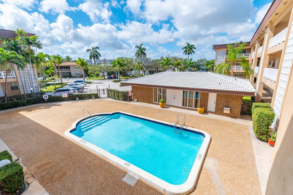 a swimming pool in front of a building with a resort style pool