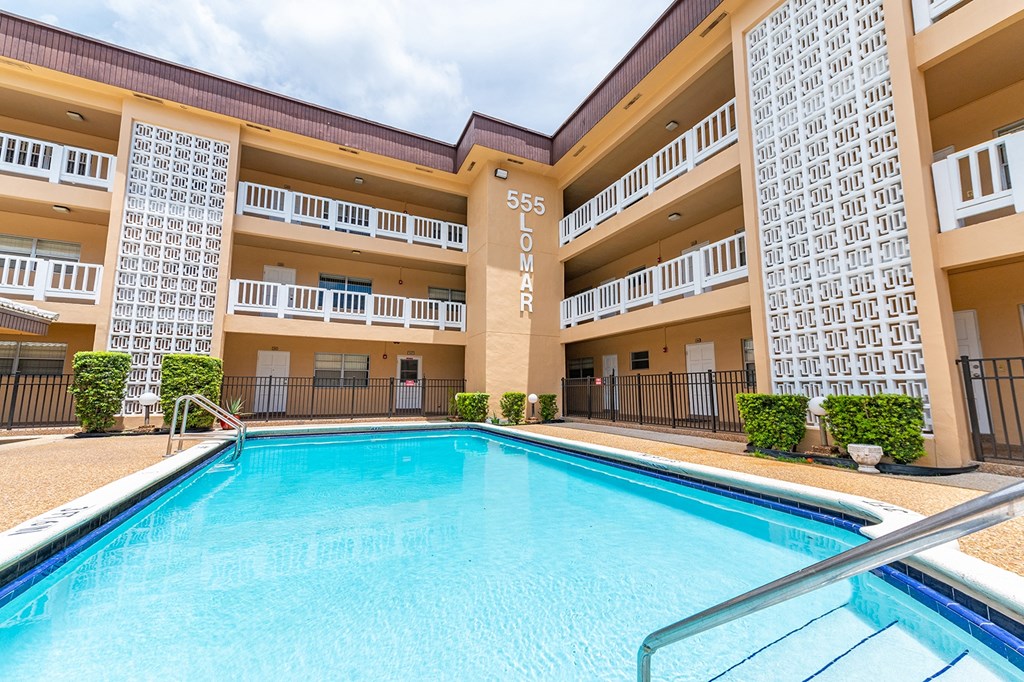 a swimming pool in front of a hotel with a blue pool