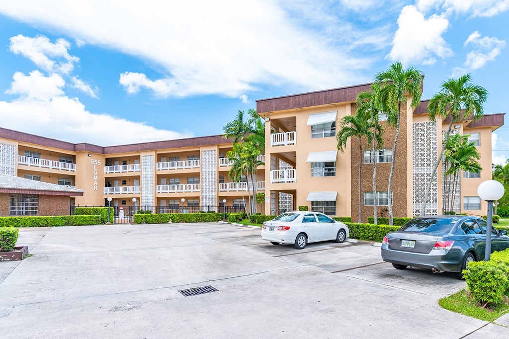 a parking lot with cars in front of an apartment building