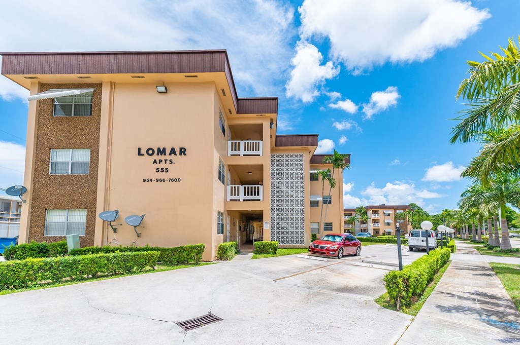 a condo building with a red car parked in front of it