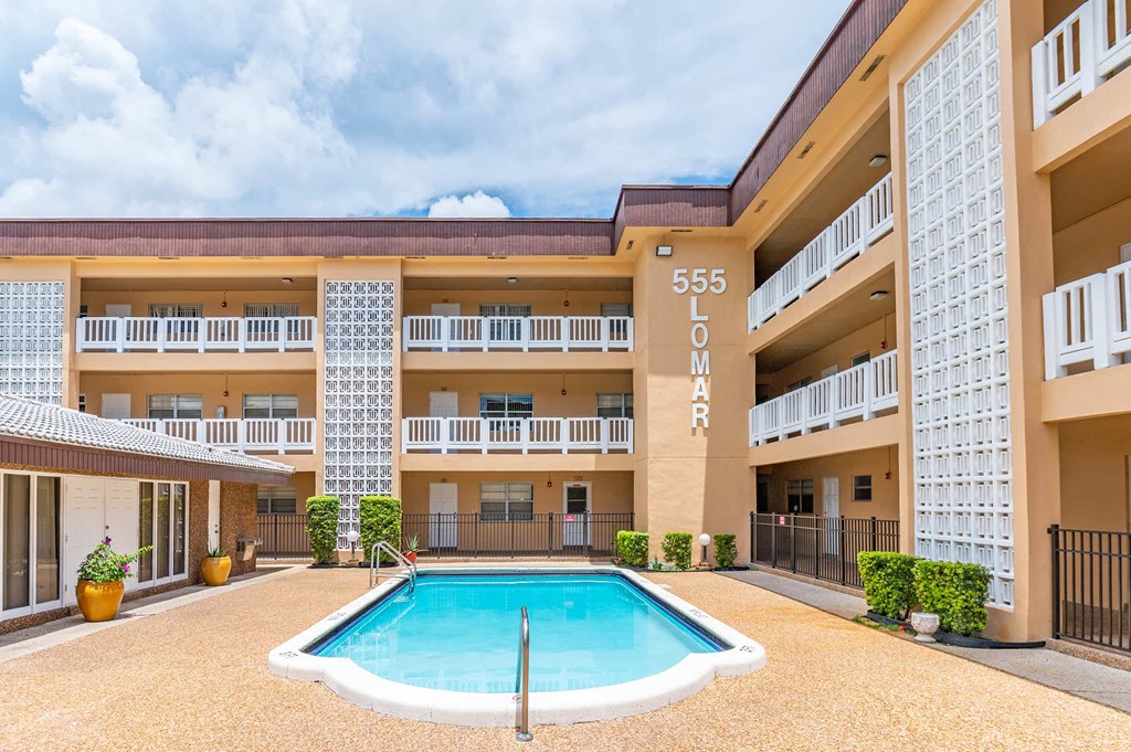 a swimming pool in front of a hotel building with a pool